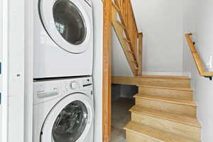 Laundry area featuring finished concrete flooring and stacked washer and clothes dryer