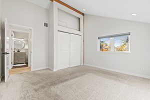 Unfurnished bedroom with high vaulted ceiling, light carpet, a closet, and recessed lighting