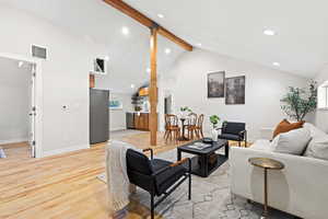 Living area with beamed ceiling, light wood-style flooring, recessed lighting, and high vaulted ceiling