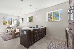 Kitchen featuring a peninsula, light countertops, dark brown cabinetry, hanging light fixtures, and concrete floors