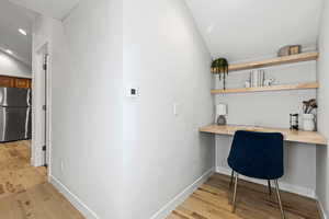 Office with built in study area, light wood-type flooring, lofted ceiling, and recessed lighting