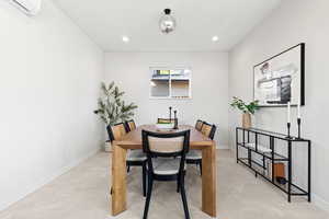 Dining area with recessed lighting, an AC wall unit, and concrete floors