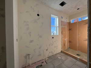 Full bathroom with a tile shower, tile patterned flooring, and windows for natural light