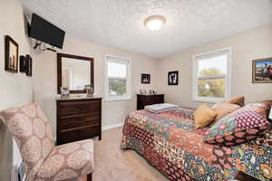 Bedroom with light carpet and a textured ceiling