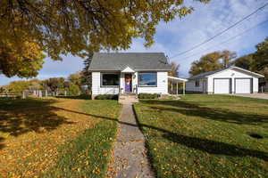 Bungalow-style home featuring a garage, roof with shingles, and an outbuilding