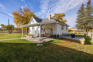 Rear view of house featuring a chimney, a patio area, and roof with shingles