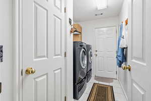 Laundry room featuring light tile patterned floors and washing machine and dryer
