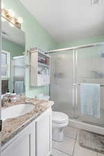 Full bath featuring light tile patterned floors, vanity, and a stall shower