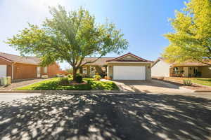 Single story home with a tiled roof, an attached garage, driveway, stucco siding, and a front lawn