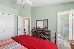 Bedroom featuring tile patterned floors, a closet, ceiling fan, and ensuite bathroom