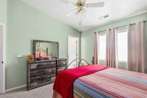 Carpeted bedroom featuring vaulted ceiling and a ceiling fan