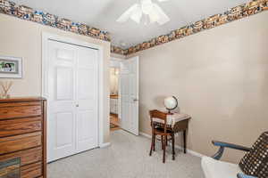 Home office with light carpet and a ceiling fan