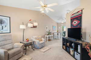 Carpeted living room featuring vaulted ceiling and ceiling fan
