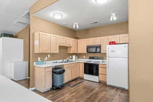 Kitchen with light brown cabinets, white appliances, light countertops, a textured ceiling, and dark wood-style flooring