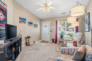 Living room featuring carpet and a ceiling fan