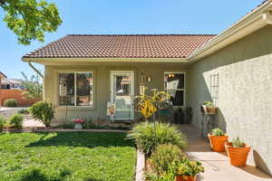 Doorway to property featuring stucco siding, a lawn, and a tile roof