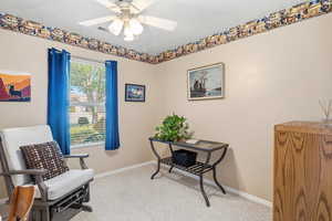 Living area with light colored carpet and a ceiling fan