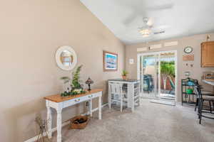 Doorway featuring carpet flooring, lofted ceiling, and a ceiling fan
