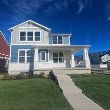 View of front of house with a porch, a front yard, board and batten siding, stone siding, and stairs