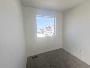 Empty room with dark colored carpet and a mountain view
