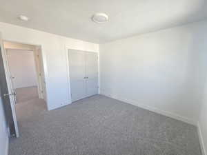 Unfurnished bedroom featuring carpet flooring, a textured ceiling, and a closet