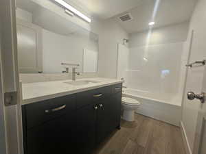 Bathroom with dark wood finished floors, vanity, and shower / washtub combination