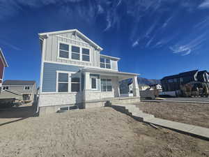 View of front of house featuring stone siding, a porch, board and batten siding, and a mountain view