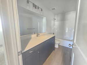 Bathroom featuring light wood-type flooring, vanity, and shower / washtub combination