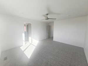 Carpeted empty room with baseboards and a ceiling fan