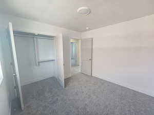 Unfurnished bedroom featuring dark colored carpet, a textured ceiling, and a closet