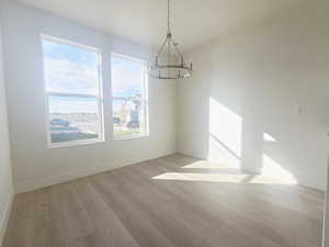Unfurnished dining area featuring light wood-style flooring and a chandelier