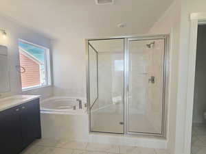 Full bathroom featuring a garden tub, a shower stall, vanity, and light marble finish floors