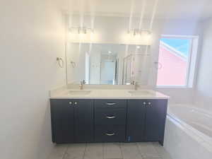 Full bathroom with double vanity, a shower stall, and a bath