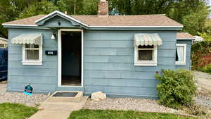 View of front facade with a chimney and roof with shingles