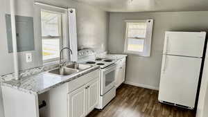 Kitchen with white appliances, light countertops, electric panel, white cabinets, and dark wood-style flooring