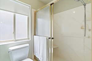 Bathroom featuring a marble finish shower and toilet