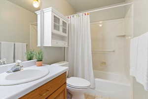 Bathroom featuring vanity, shower / bath combination with curtain, light tile patterned floors, and a textured ceiling