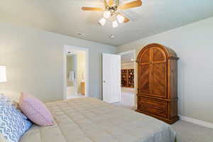 Bedroom with light carpet, ceiling fan, and ensuite bath
