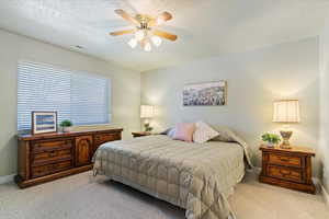 Carpeted bedroom with a textured ceiling and a ceiling fan
