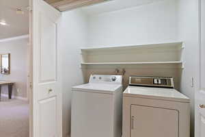 Laundry room featuring carpet floors, separate washer and dryer, and ornamental molding