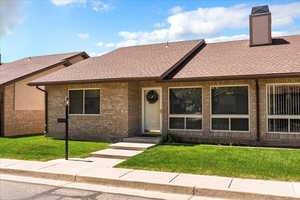 View of front of home featuring a front yard, roof with shingles, and brick siding