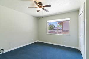 Unfurnished bedroom featuring a closet, carpet flooring, a textured ceiling, and a ceiling fan
