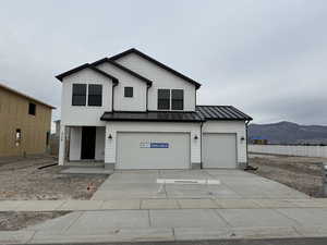 Modern farmhouse style home featuring a standing seam roof, a metal roof, concrete driveway, a mountain view, and a garage