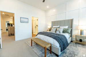 Bedroom featuring a decorative wall, light carpet, recessed lighting, ceiling fan, and ensuite bath
