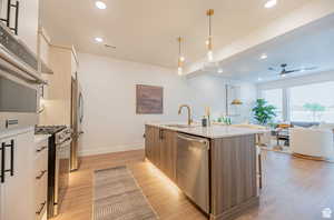 Kitchen featuring light brown cabinets, pendant lighting, stainless steel appliances, light wood-type flooring, and open floor plan