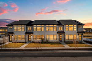 View of front facade with a front yard, a standing seam roof, stucco siding, and a metal roof