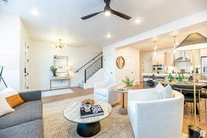 Living room with stairway, recessed lighting, a chandelier, light wood finished floors, and ceiling fan