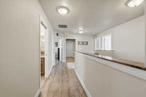 Hall with light wood-style floors and an upstairs landing