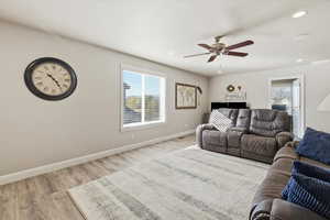 Living room with light wood-type flooring, recessed lighting, and a ceiling fan