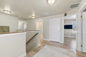 Hall featuring an upstairs landing and light wood-style floors